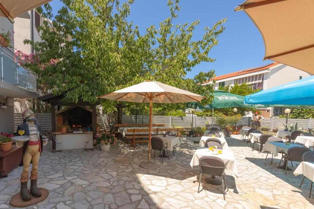 Garden terrace with dining tables and barbecue at Pansion Pirat