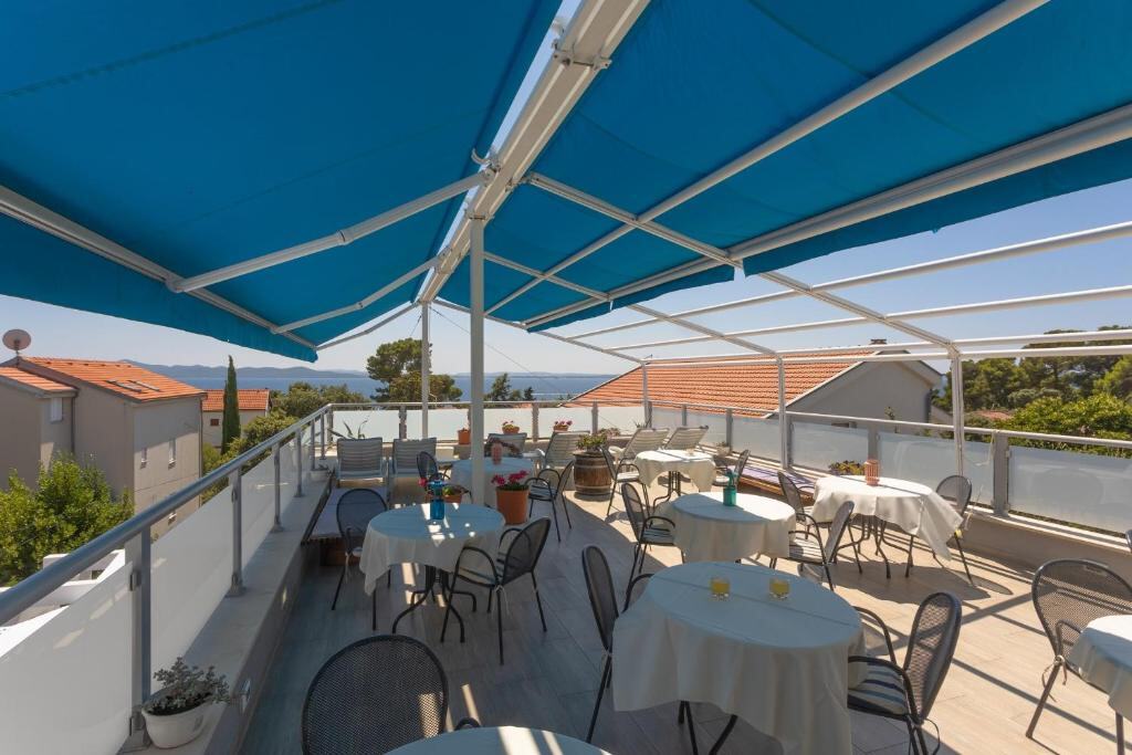 Shared sea-view terrace with tables and blue awning at Pansion Pirat